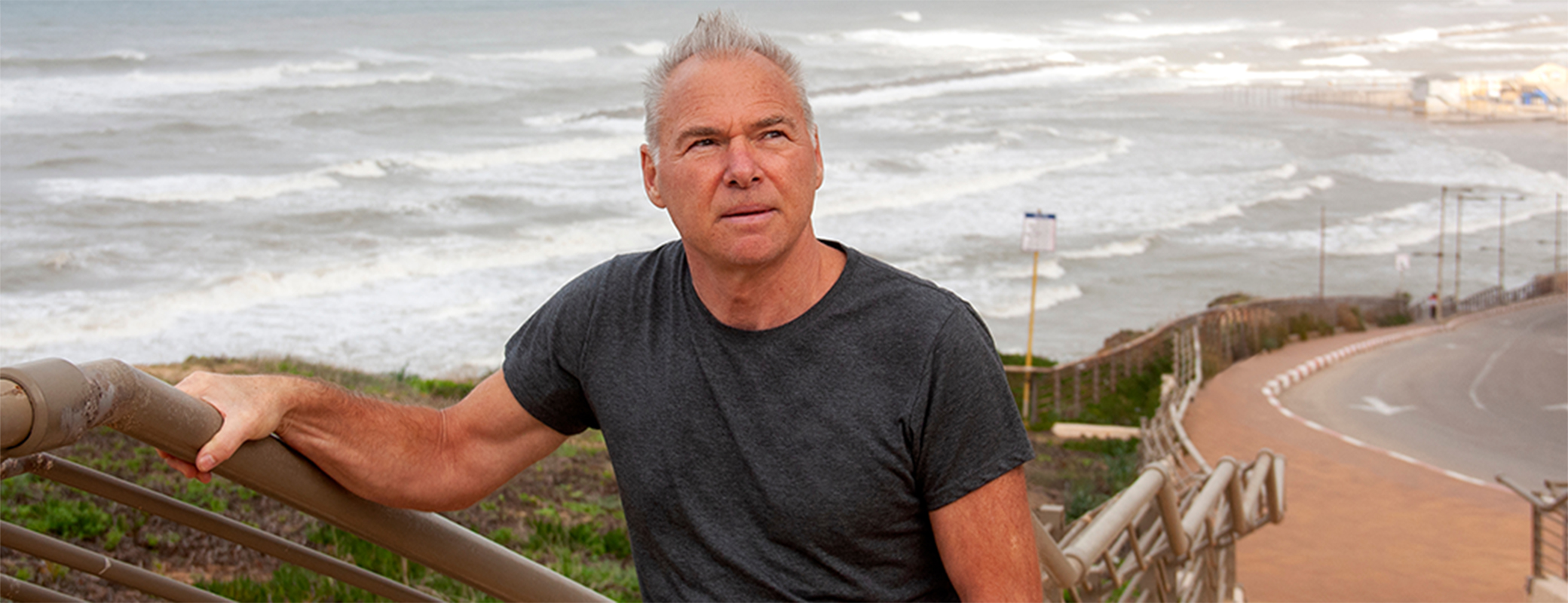 Image of senior man walking up steps above a beach